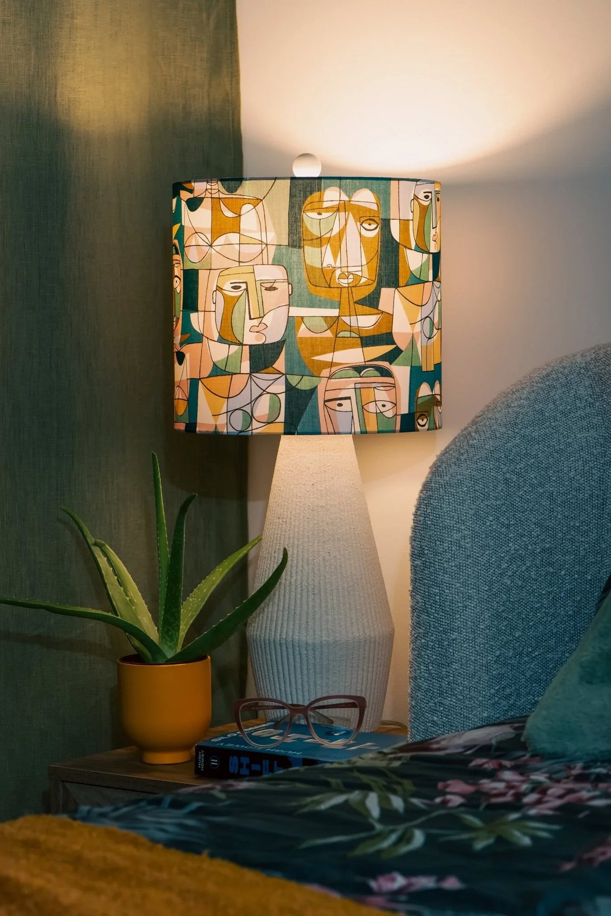 Daydreamer drum lampshade in Liberty Carnaby Cast cotton, glowing on a wooden bedside table in a cozy bedroom setting